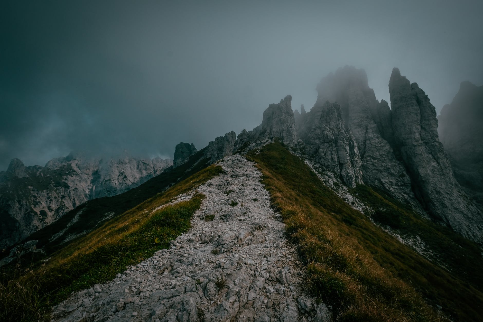 green grass field and mountain under gray clouds outdoor risk from weather