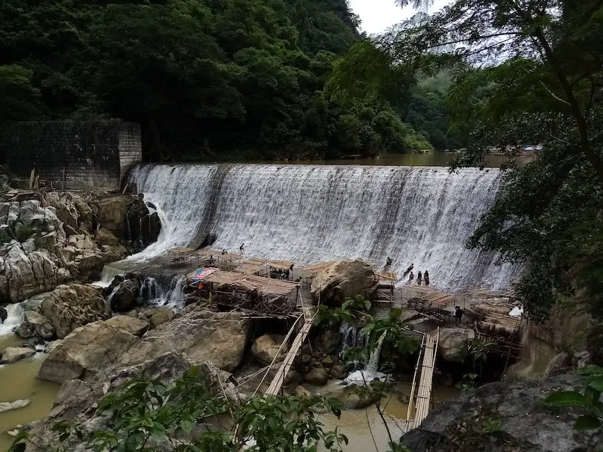 Image of a person wearing waterproof hiking pants facing a waterfall in a lush forest Waterproof Hiking Pants